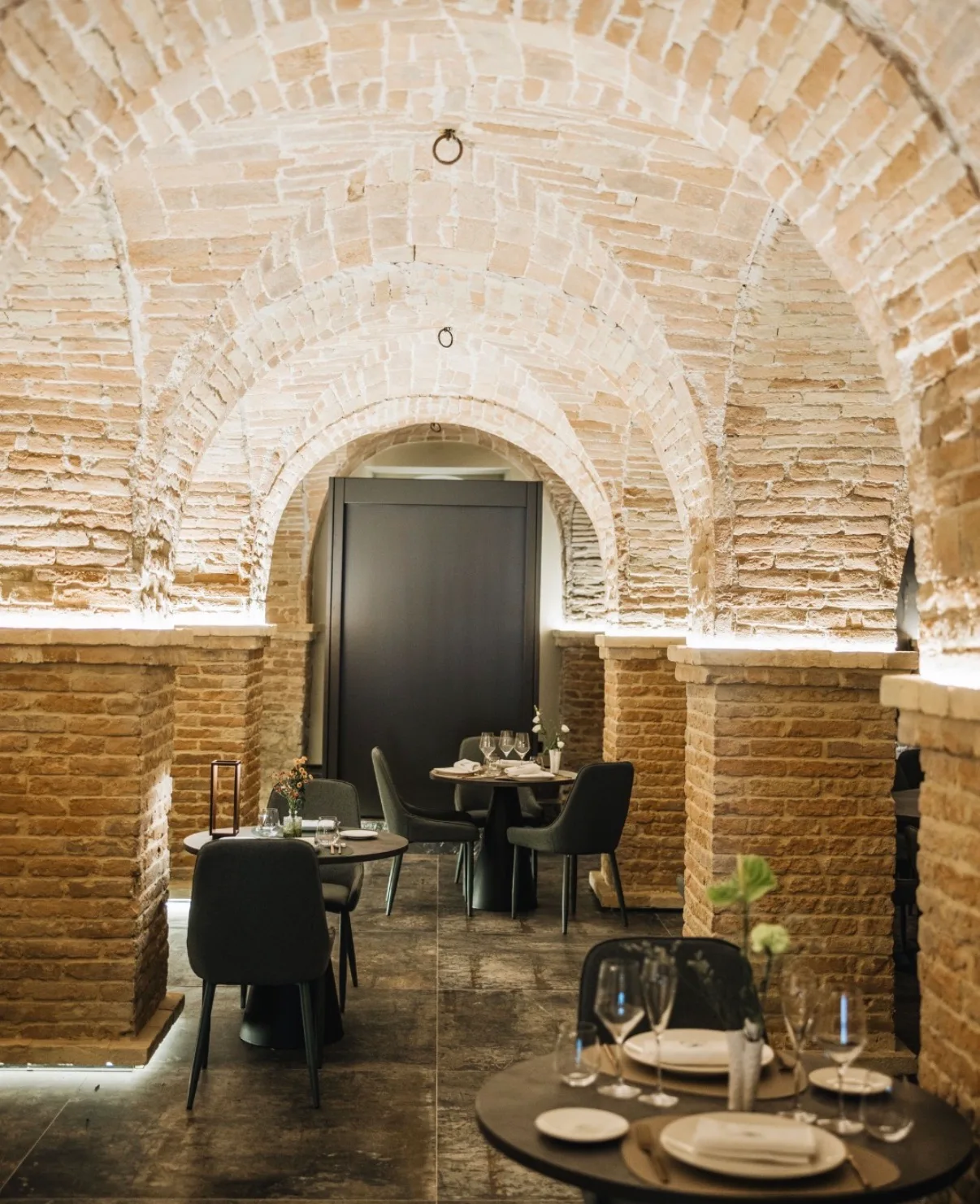 La sala di Macallè sotto le volte a crociera in mattoni, con i tavoli rotondi apparecchiati